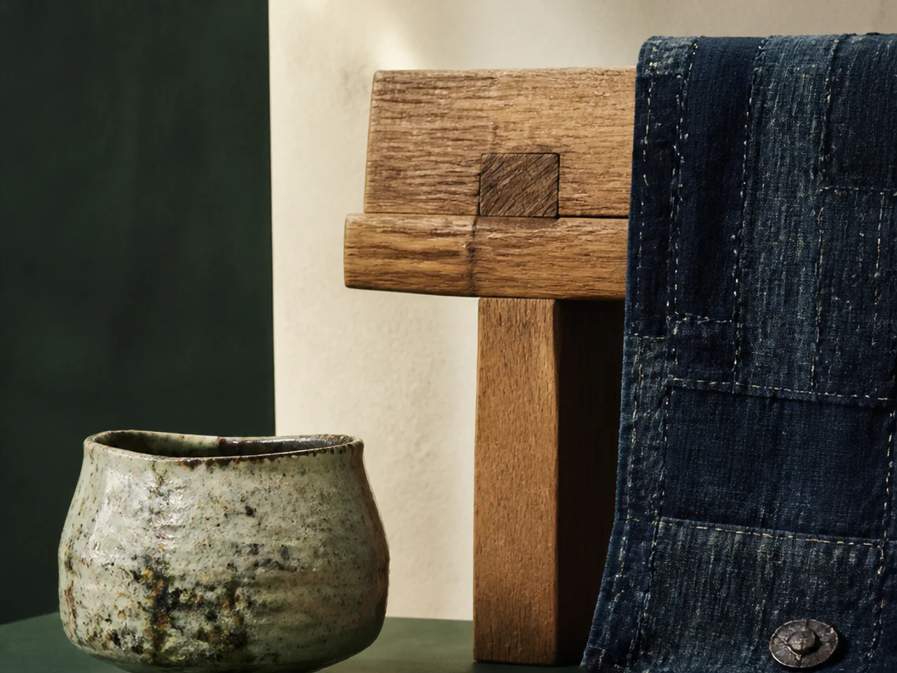 Patinated ceramic and indigo textile displayed with an oak object.